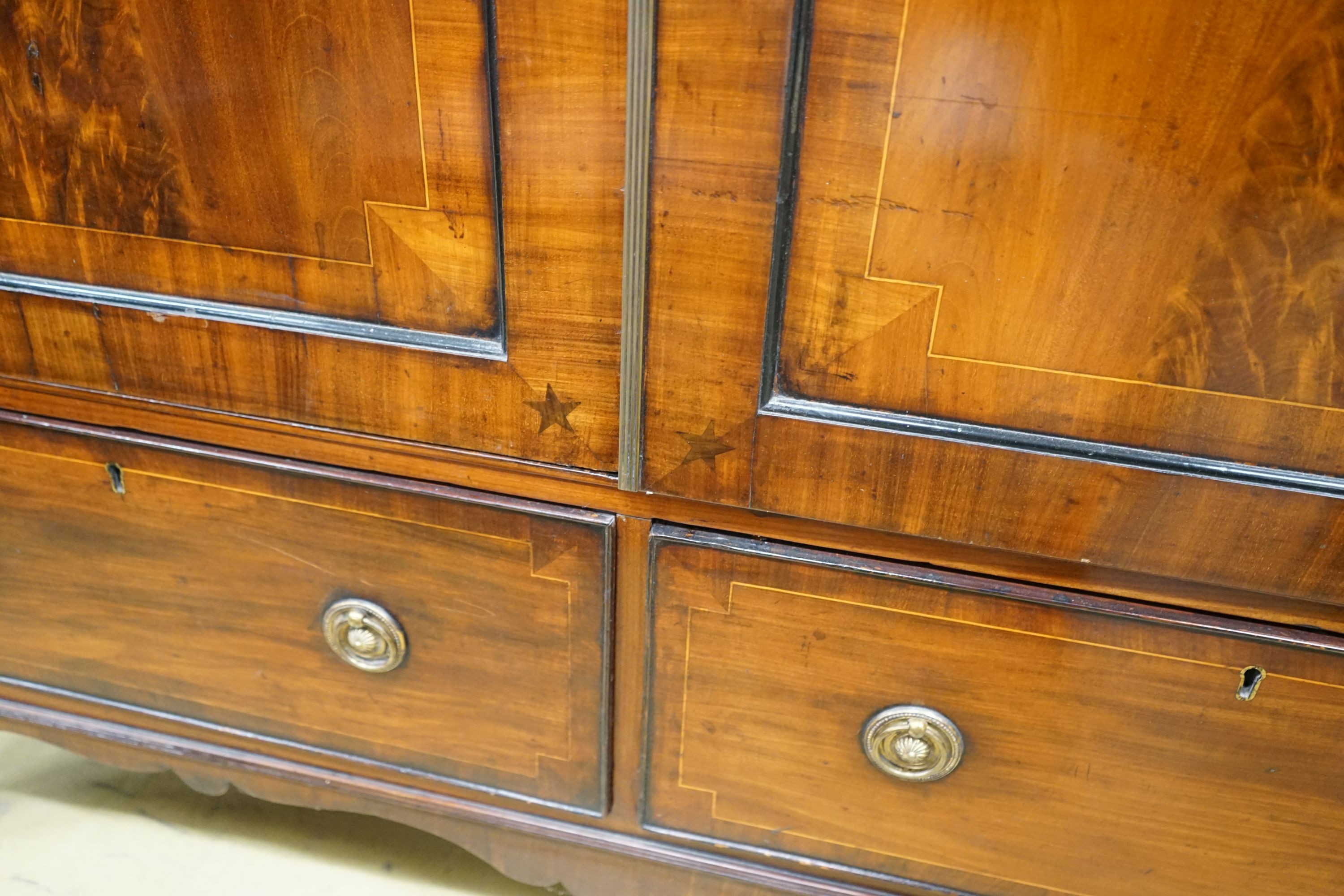 A 19th century mahogany linen press of small proportions, with panelled flamed mahogany doors centered with inlaid star motifs, width 133cm, depth 60cm, height 196cm
